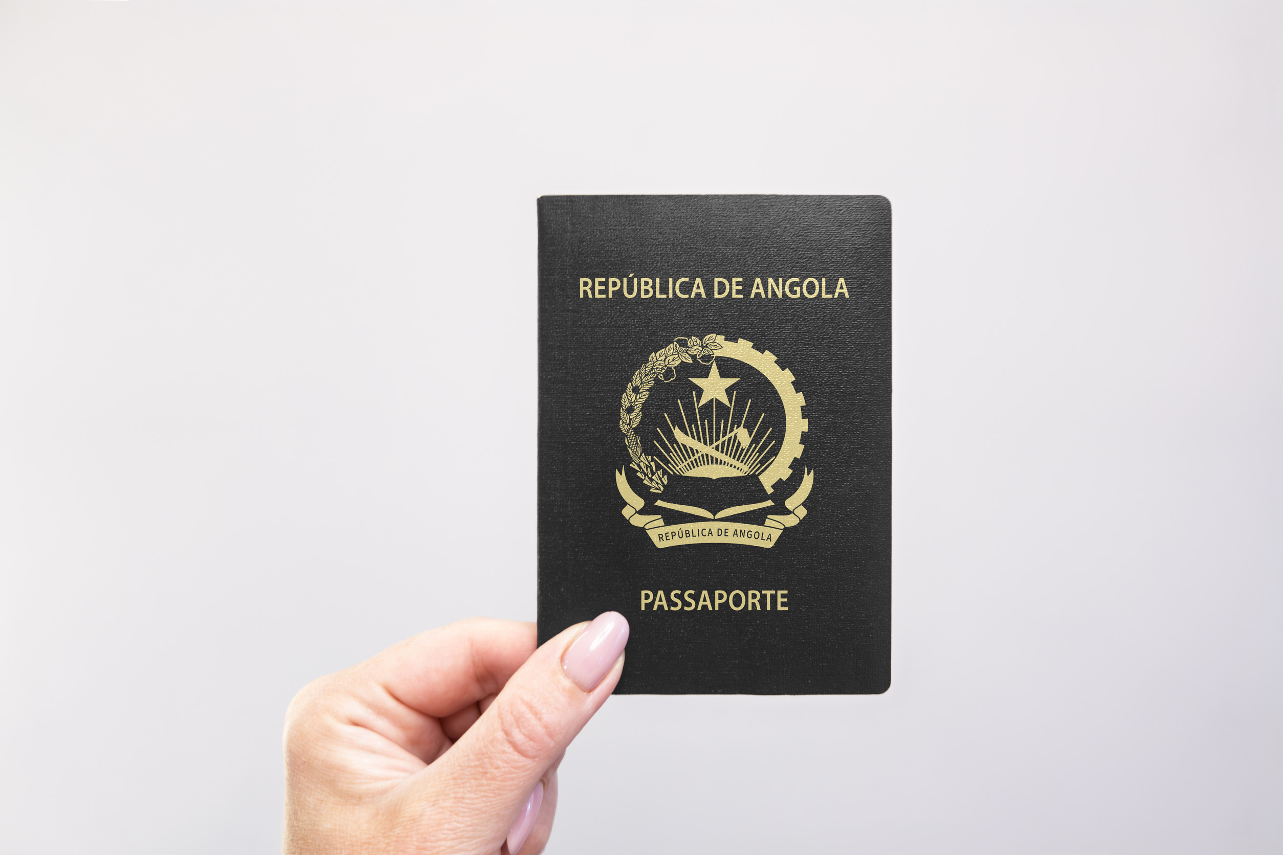 Angola Passport Held In Hand Against A Plain White