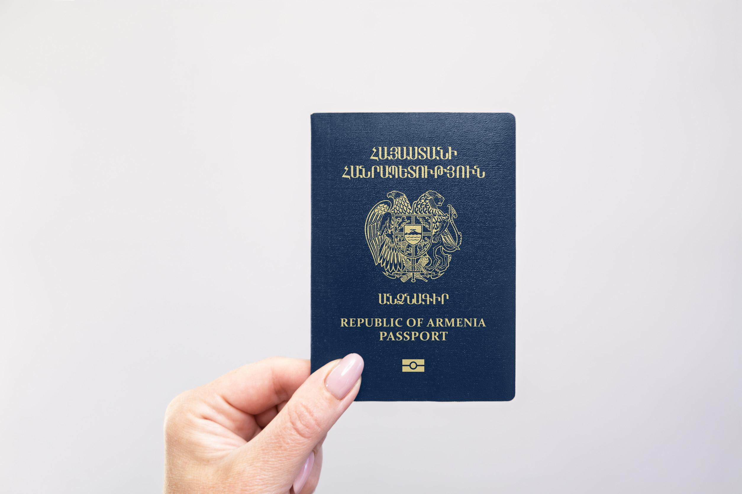 Armenian Passport Held In Hand Against A Plain White Background