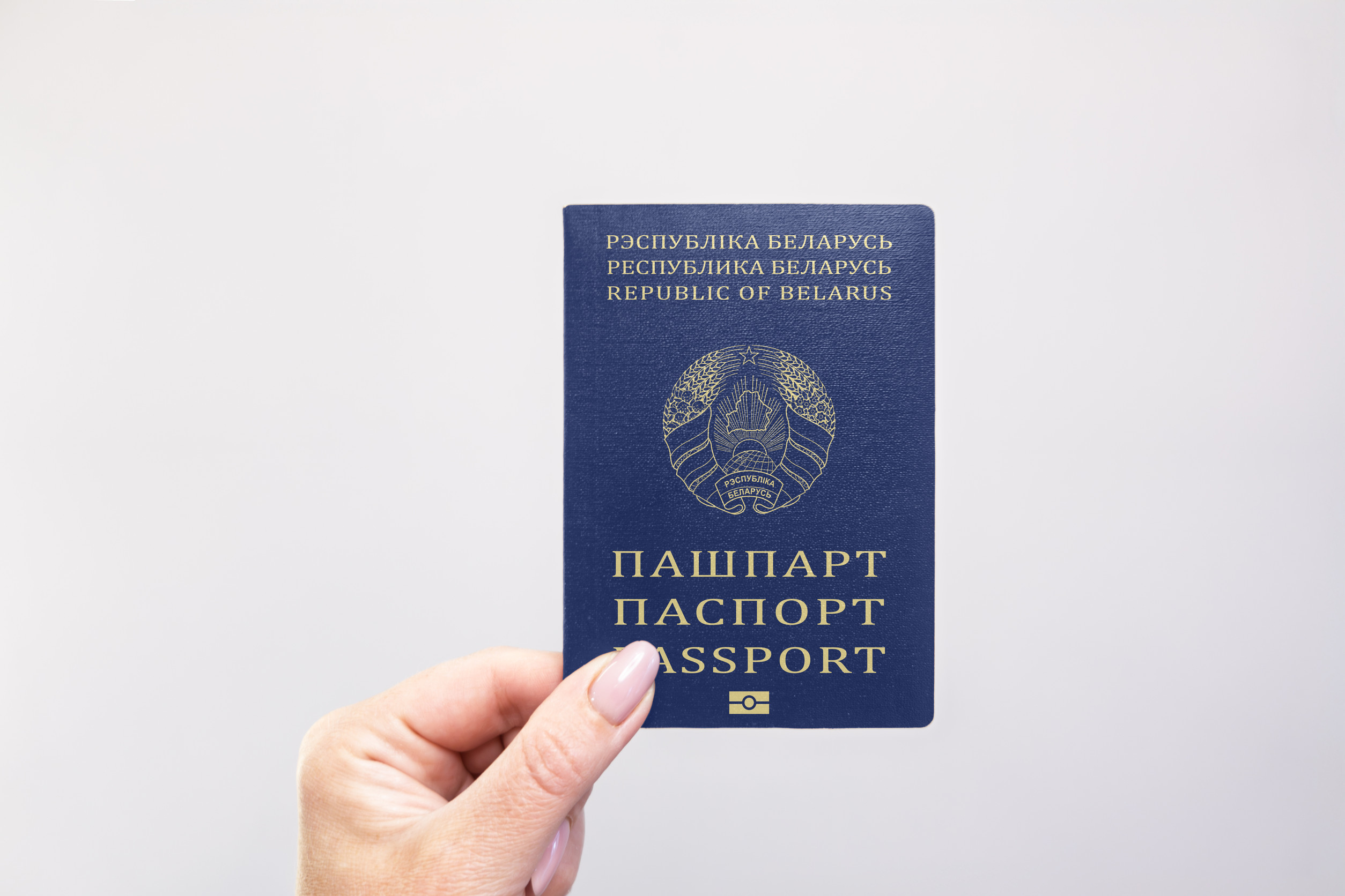 Belarus Passport Held In Hand Against A Plain White Background
