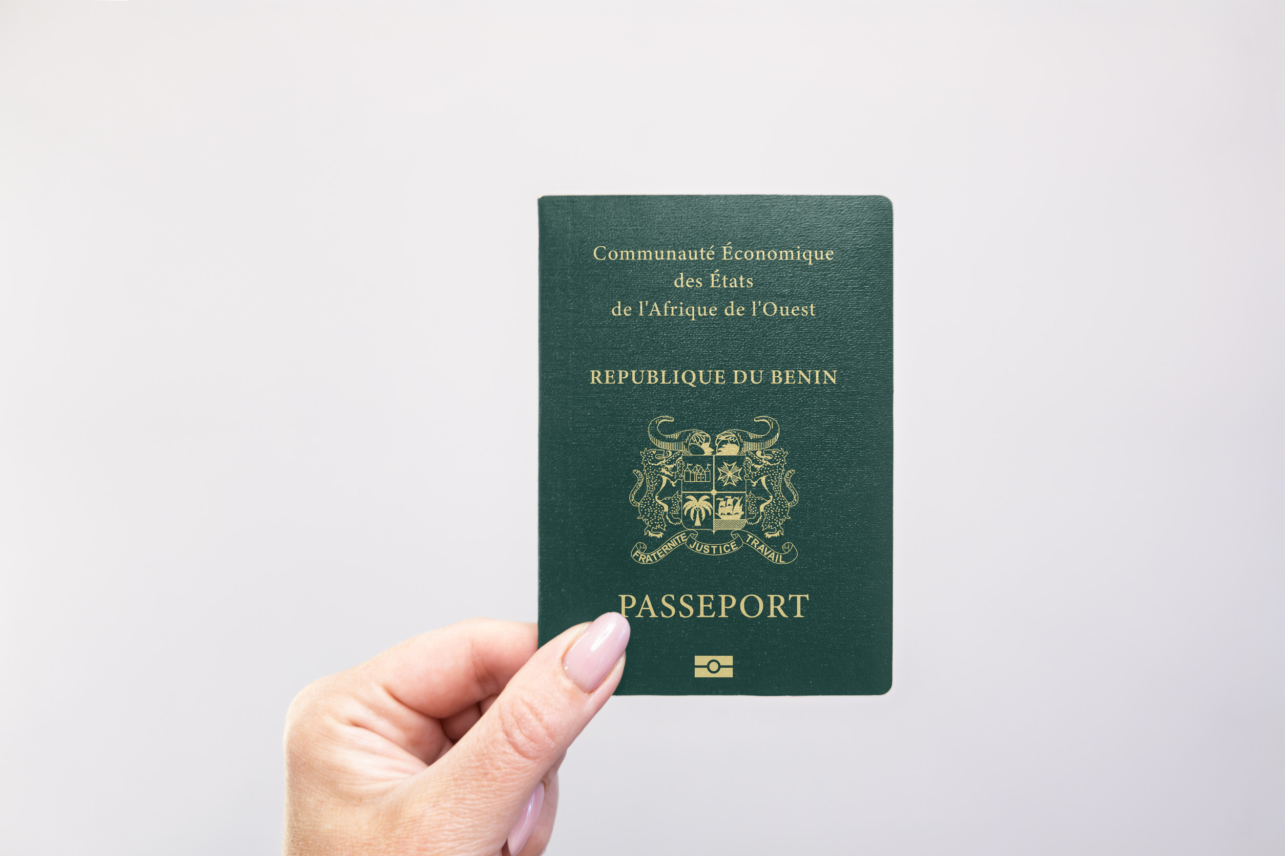 Benin Passport Held In Hand Against A Plain White Background