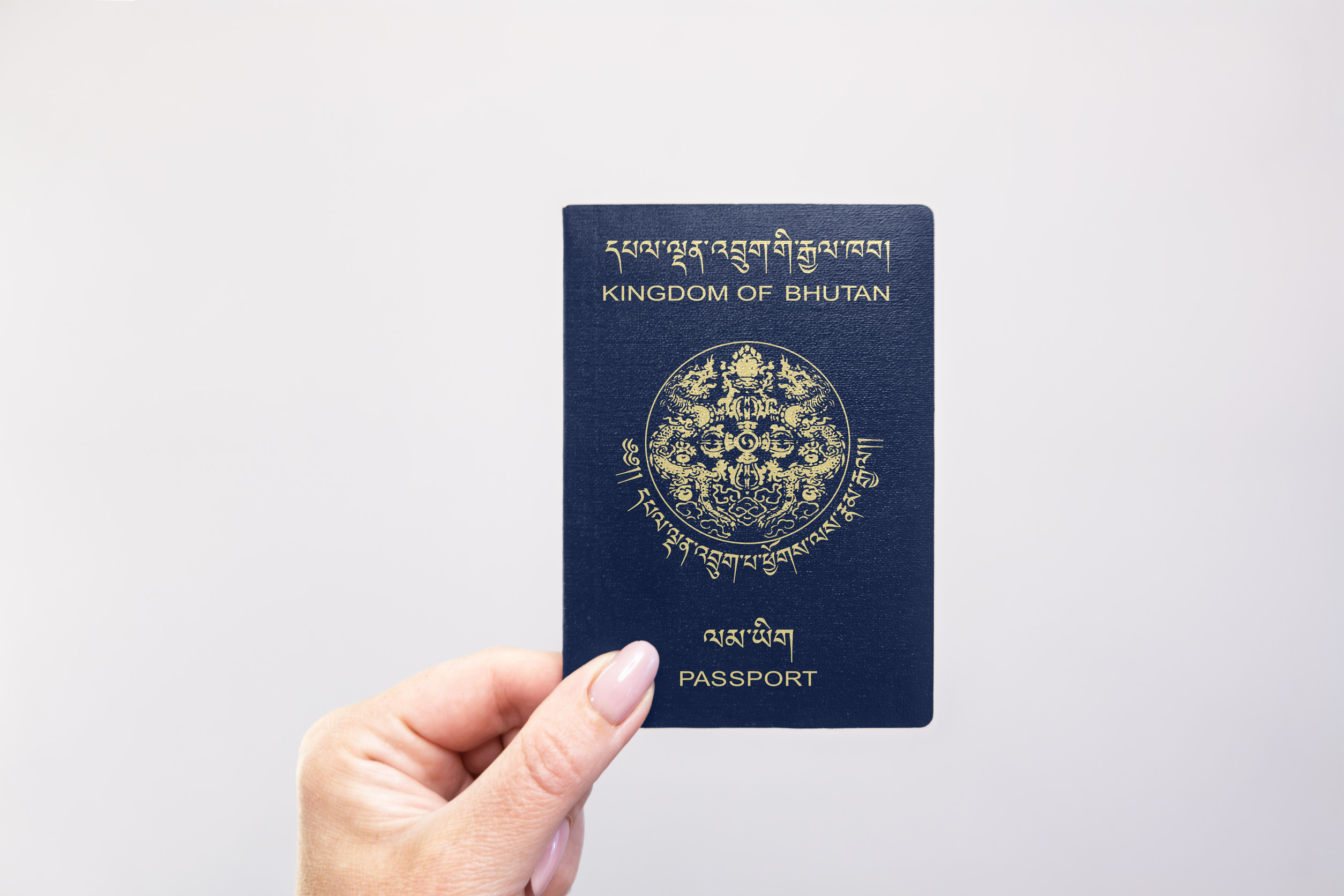  Bhutan Passport Held In Hand Against A Plain White Background