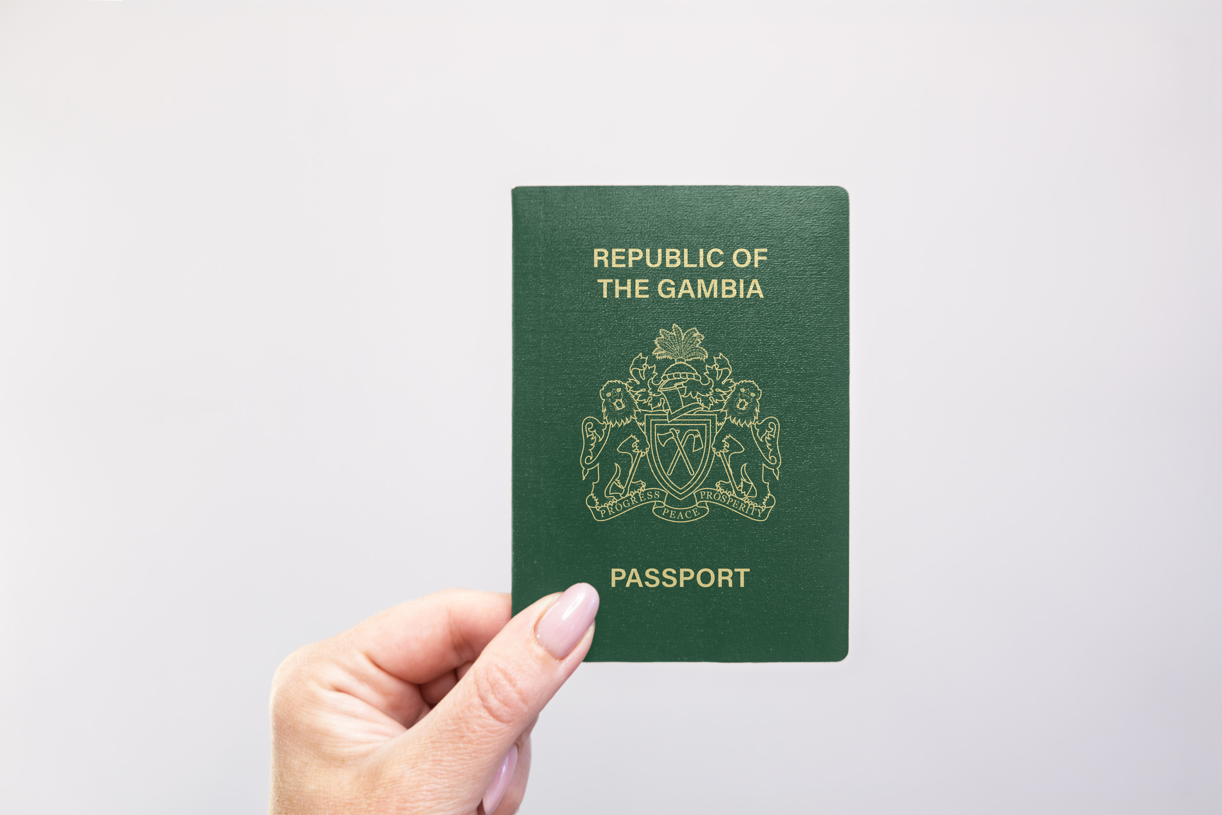 Gambia Passport Held In Hand Against A Plain