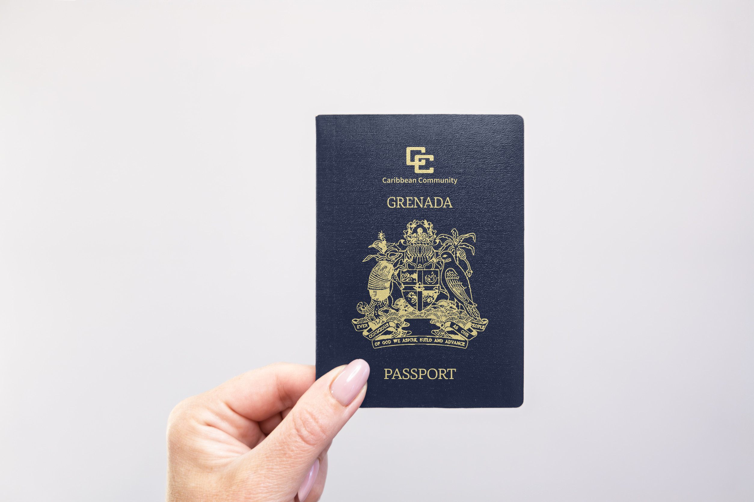 Grenada Passport Held In Hand Against A Plain White Background