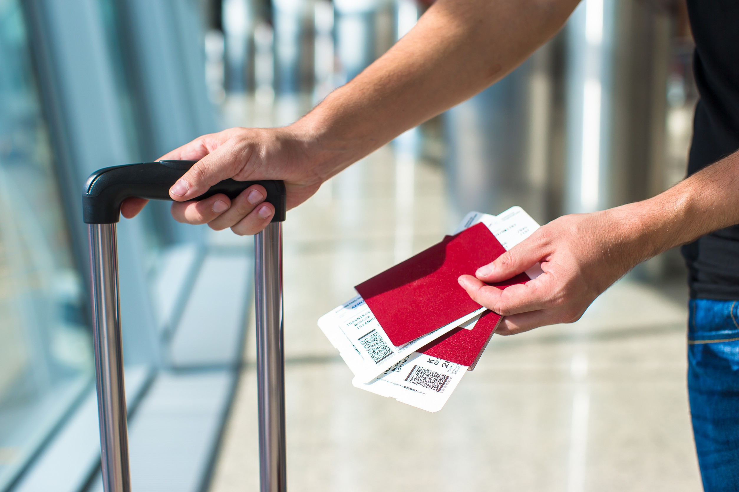 closeup of man holding passports and boarding pass at airport