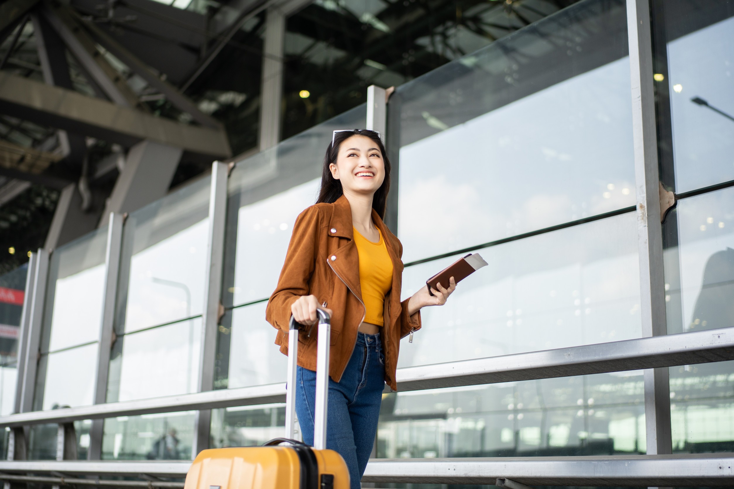 happy young asian woman traveler using smartphone and holding