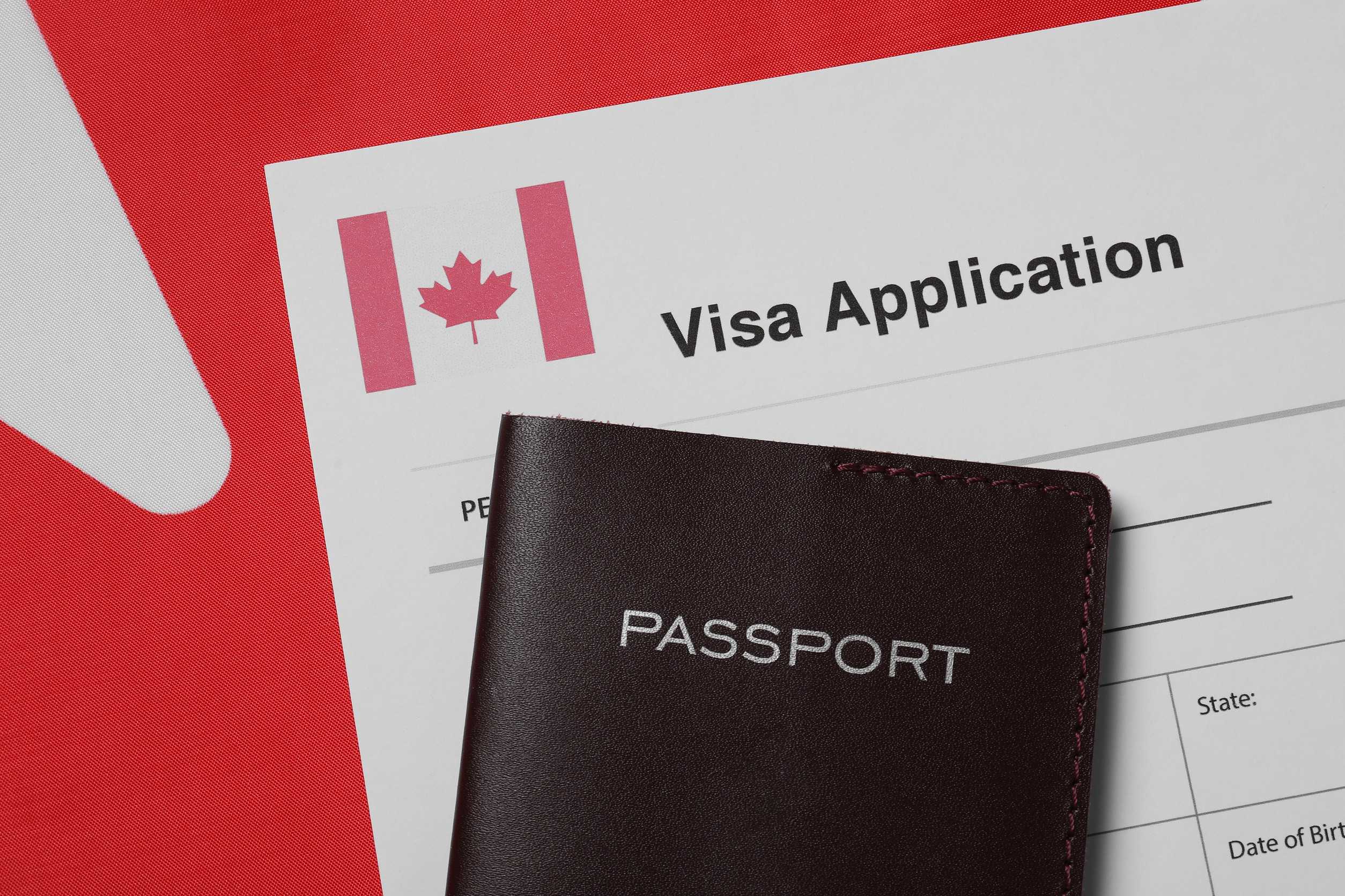 immigration to canada visa application form and passport on flag