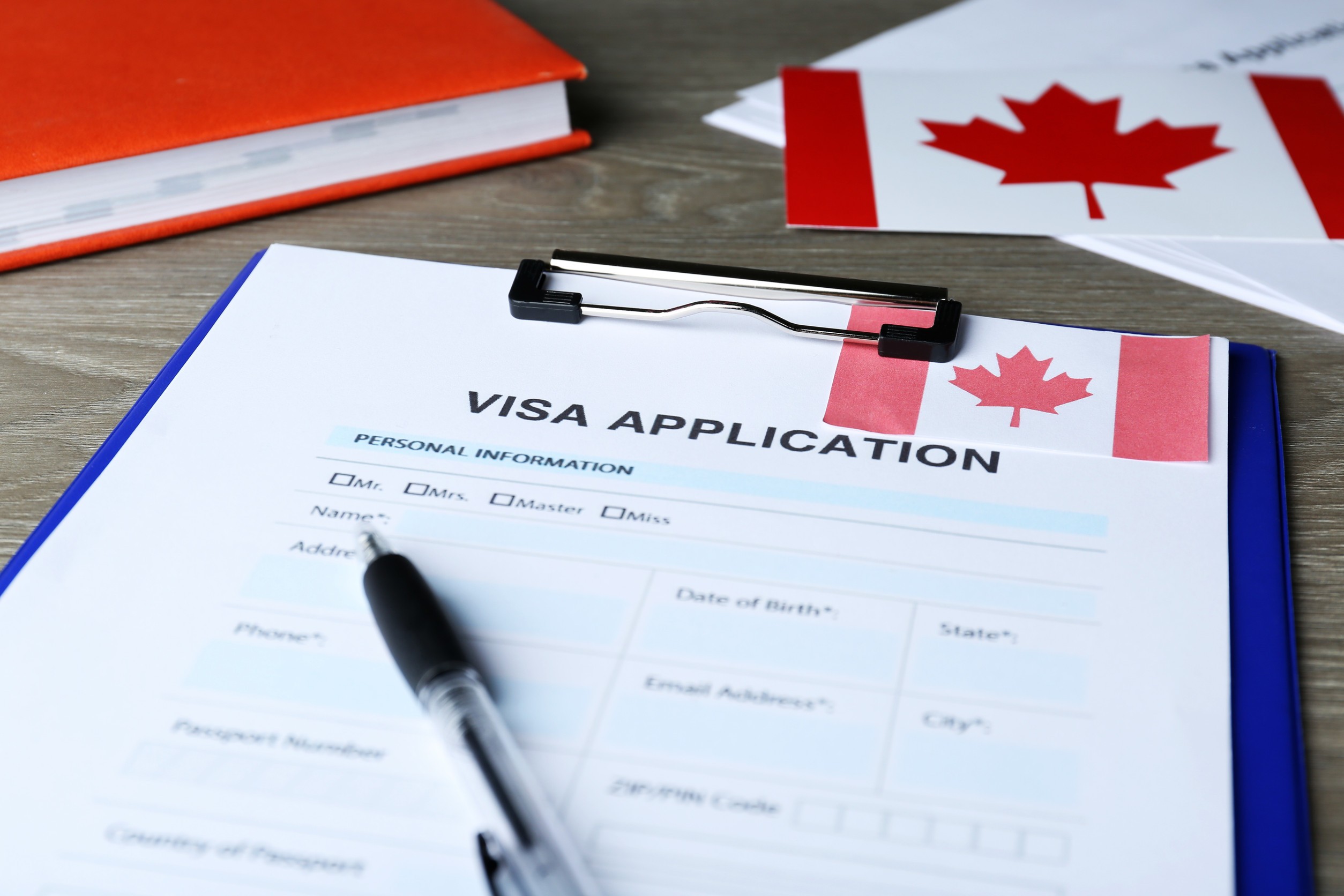 visa application form for immigration to canada and pen on woodens table