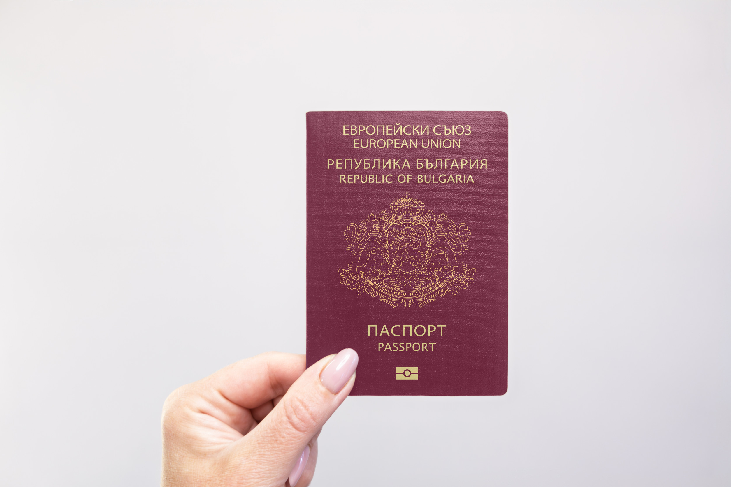Passport In Hand Against A Plain White Background